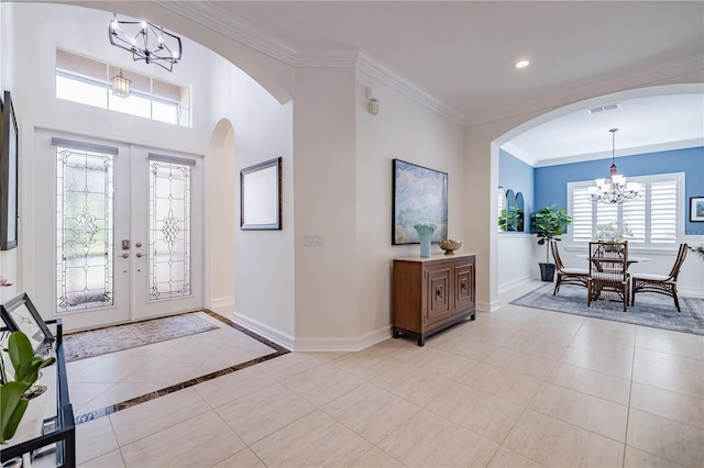 tiled foyer entrance featuring an inviting chandelier, crown molding, and french doors