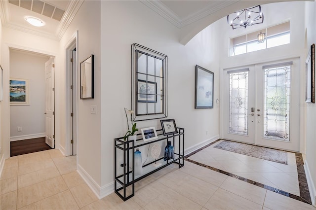 foyer with a chandelier, french doors, ornamental molding, and light tile patterned flooring