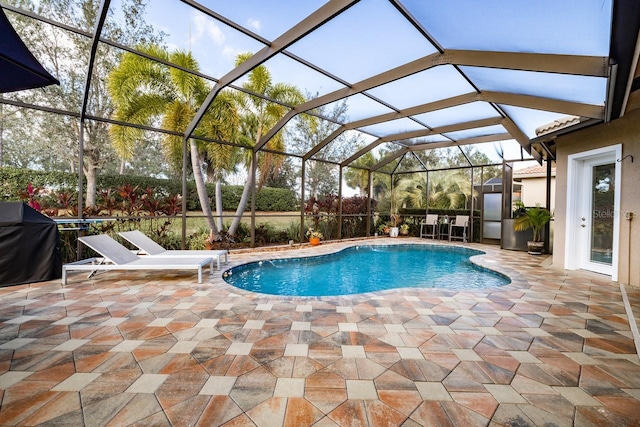 view of pool with area for grilling, a patio, and glass enclosure