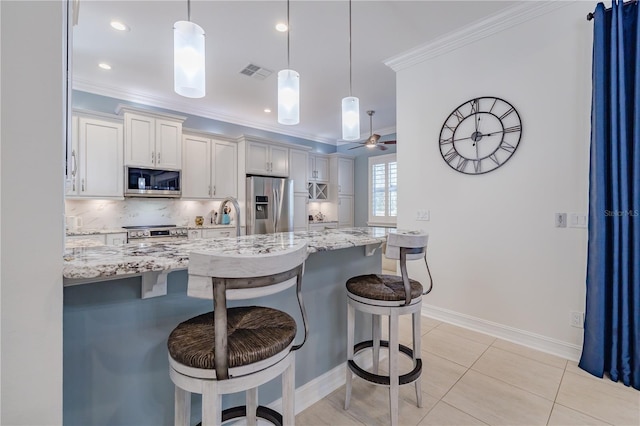 kitchen with a breakfast bar, light stone counters, stainless steel appliances, and decorative light fixtures