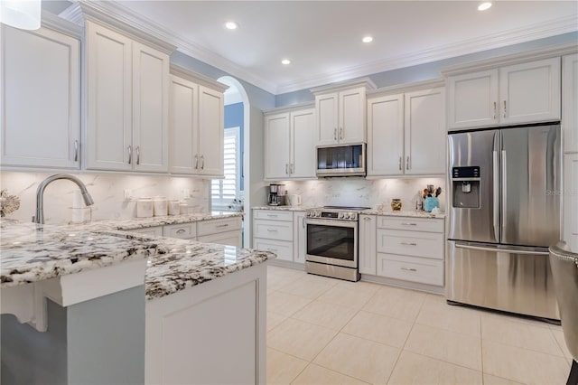 kitchen with stainless steel appliances, tasteful backsplash, light stone counters, crown molding, and white cabinets