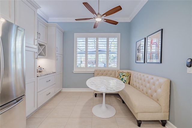 living area featuring breakfast area, ceiling fan, ornamental molding, and light tile patterned flooring