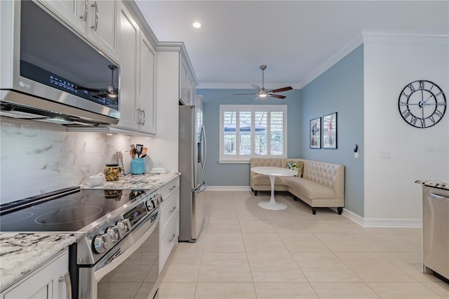 kitchen with white cabinetry, light stone counters, ornamental molding, and appliances with stainless steel finishes