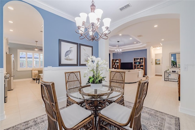 tiled dining area with ceiling fan with notable chandelier, a raised ceiling, and crown molding