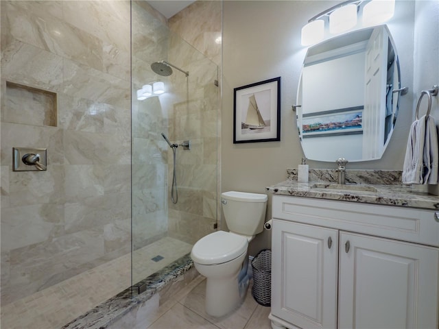 bathroom featuring a tile shower, tile patterned flooring, vanity, and toilet