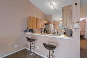 kitchen with a kitchen breakfast bar, stainless steel fridge, kitchen peninsula, and light brown cabinetry