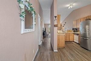 corridor featuring dark hardwood / wood-style flooring and vaulted ceiling