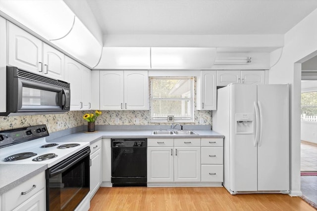 kitchen featuring black appliances, white cabinetry, and sink