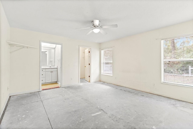 unfurnished bedroom featuring ceiling fan, a spacious closet, connected bathroom, and a closet