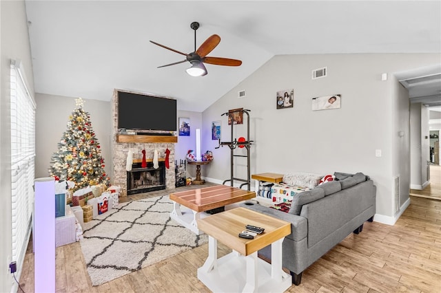 living room with ceiling fan, a fireplace, lofted ceiling, and light hardwood / wood-style flooring