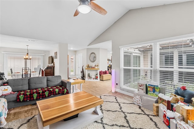 living room featuring ceiling fan with notable chandelier, light hardwood / wood-style flooring, and lofted ceiling