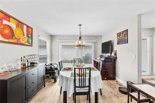 dining area featuring light hardwood / wood-style flooring, a textured ceiling, and a notable chandelier