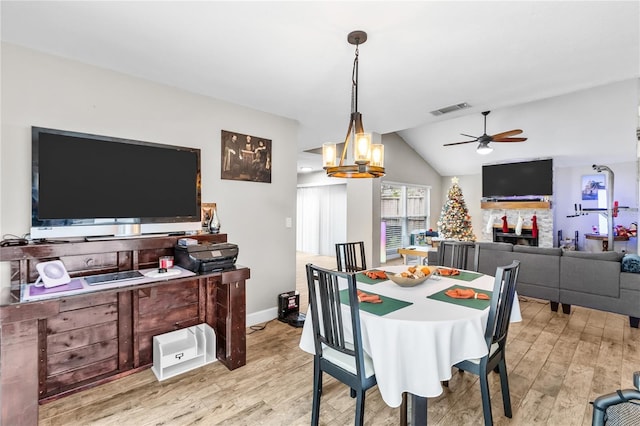 dining space featuring light hardwood / wood-style flooring, ceiling fan with notable chandelier, and lofted ceiling