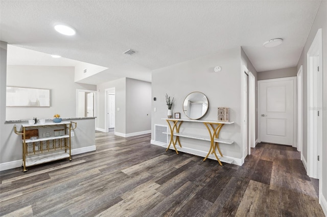 interior space with a textured ceiling and dark hardwood / wood-style floors