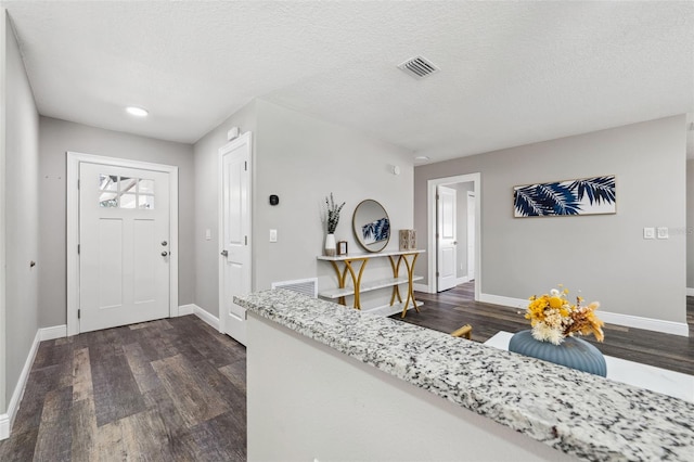 foyer entrance with dark wood-type flooring and a textured ceiling