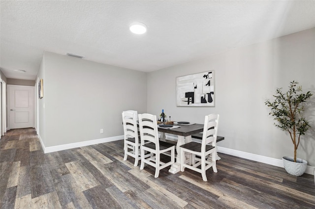 dining space featuring dark wood-type flooring and a textured ceiling