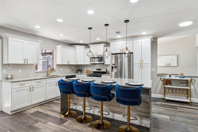 kitchen featuring pendant lighting, white cabinets, sink, a kitchen island, and stainless steel appliances