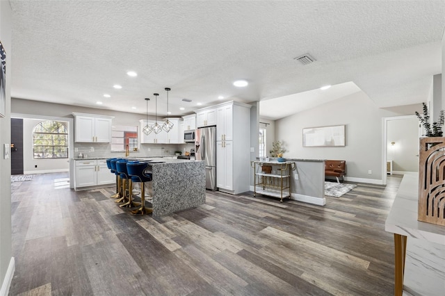 kitchen featuring a breakfast bar, a center island, stainless steel appliances, and hanging light fixtures