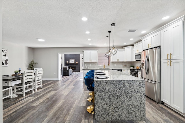 kitchen with a center island, white cabinets, decorative backsplash, decorative light fixtures, and stainless steel appliances