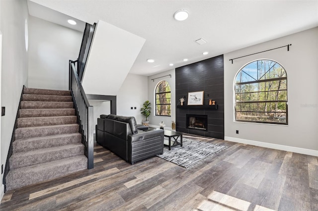 living room with lofted ceiling, a large fireplace, and dark wood-type flooring