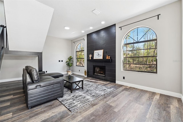 living room with dark hardwood / wood-style floors and a tiled fireplace