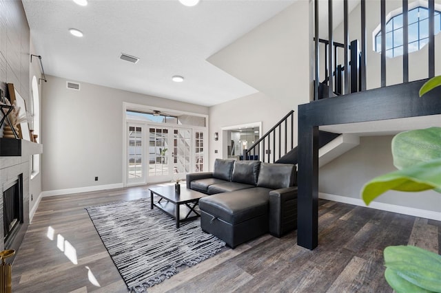 living room with a tile fireplace, a textured ceiling, ceiling fan, and dark wood-type flooring