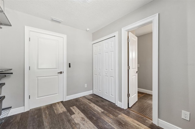 interior space with a textured ceiling, dark hardwood / wood-style floors, and a closet