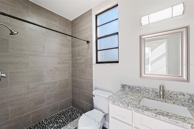 bathroom with vanity, toilet, and tiled shower