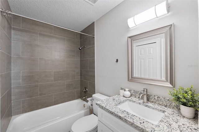 full bathroom featuring toilet, vanity, a textured ceiling, and tiled shower / bath