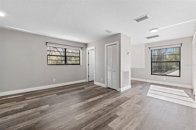 unfurnished room featuring dark hardwood / wood-style flooring and a textured ceiling