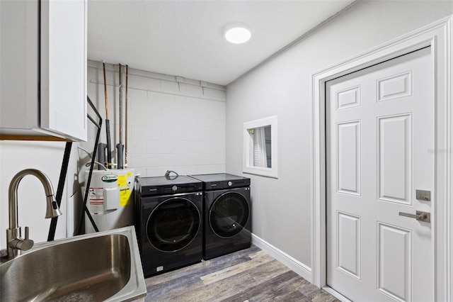 laundry area with cabinets, light wood-type flooring, water heater, sink, and washing machine and clothes dryer