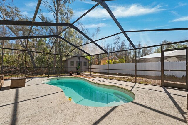 view of swimming pool featuring glass enclosure, a patio area, and an outbuilding