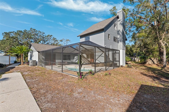 back of house featuring a lanai, a patio area, central air condition unit, and a fenced in pool