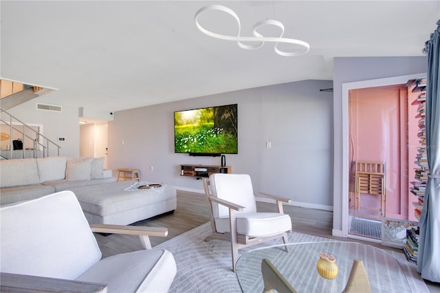 living room with a notable chandelier, wood-type flooring, and lofted ceiling