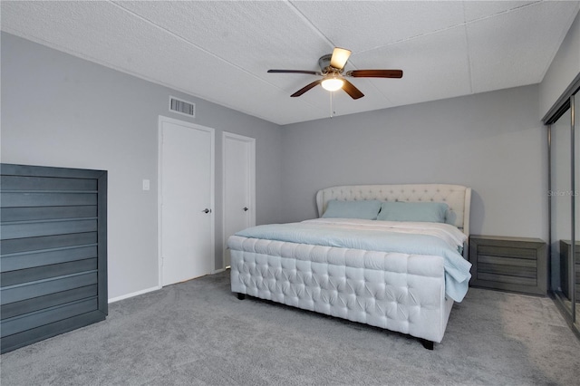 carpeted bedroom with ceiling fan and a textured ceiling