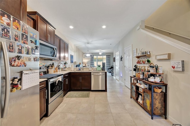 kitchen with kitchen peninsula, appliances with stainless steel finishes, dark brown cabinets, light tile patterned floors, and decorative light fixtures