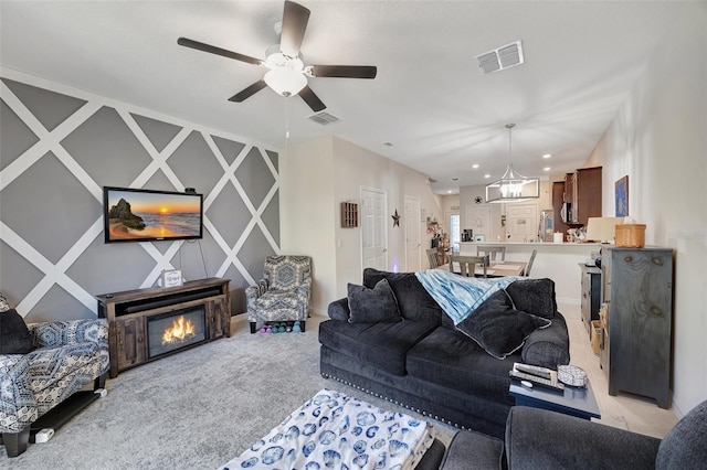 carpeted living room featuring ceiling fan with notable chandelier