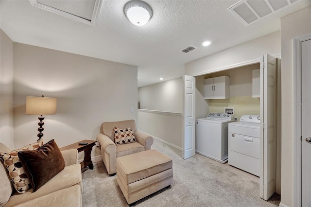 washroom featuring cabinets, independent washer and dryer, a textured ceiling, and light carpet