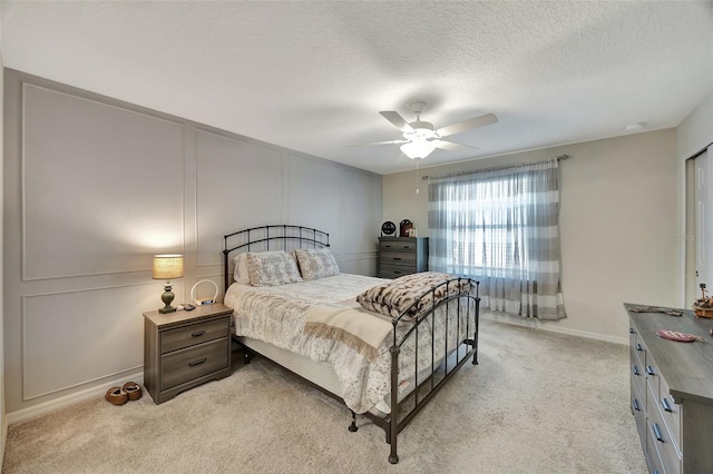 bedroom with ceiling fan, light colored carpet, and a textured ceiling