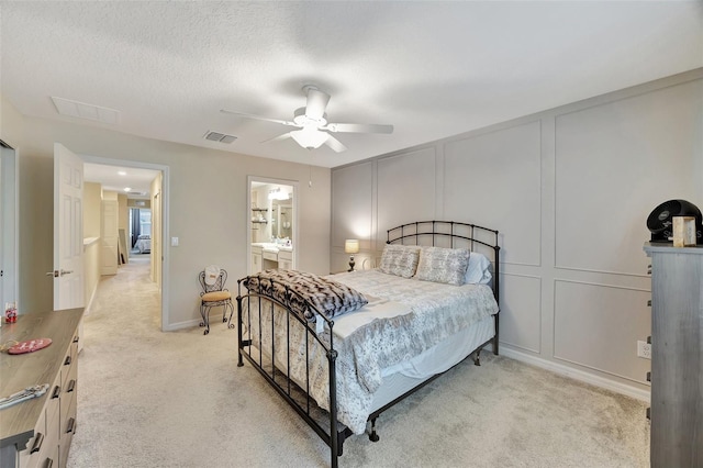 carpeted bedroom with a textured ceiling, ensuite bathroom, and ceiling fan