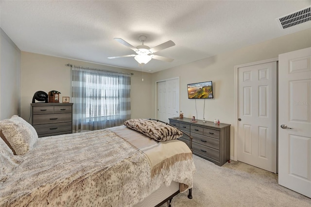 carpeted bedroom with ceiling fan and a textured ceiling