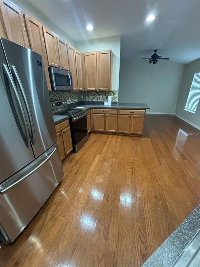 kitchen featuring ceiling fan, stainless steel appliances, light hardwood / wood-style flooring, backsplash, and kitchen peninsula