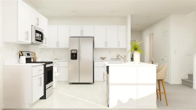 kitchen with stainless steel appliances, white cabinetry, a kitchen island with sink, and sink