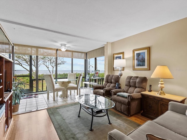 living room featuring floor to ceiling windows, ceiling fan, and light wood-type flooring