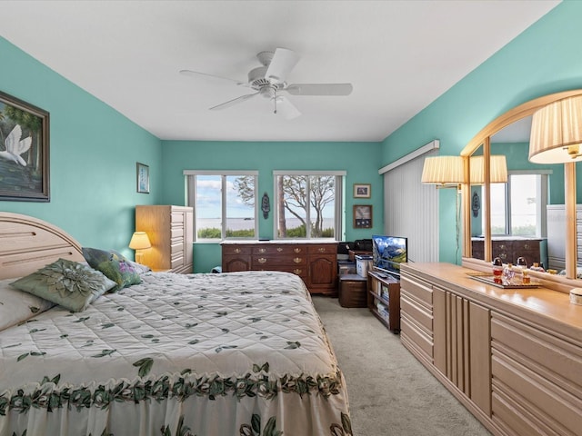 bedroom featuring multiple windows, ceiling fan, and light carpet