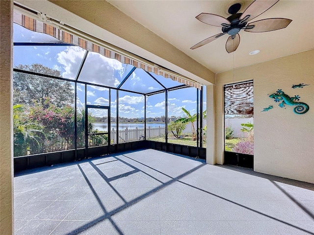 unfurnished sunroom featuring ceiling fan and a water view