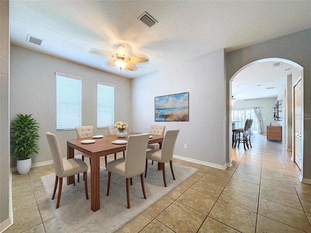 dining space with ceiling fan, a textured ceiling, and light tile patterned floors