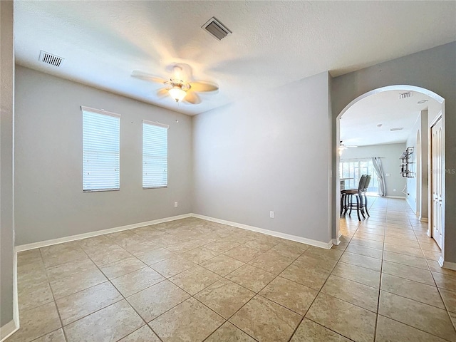 tiled empty room featuring ceiling fan and a textured ceiling