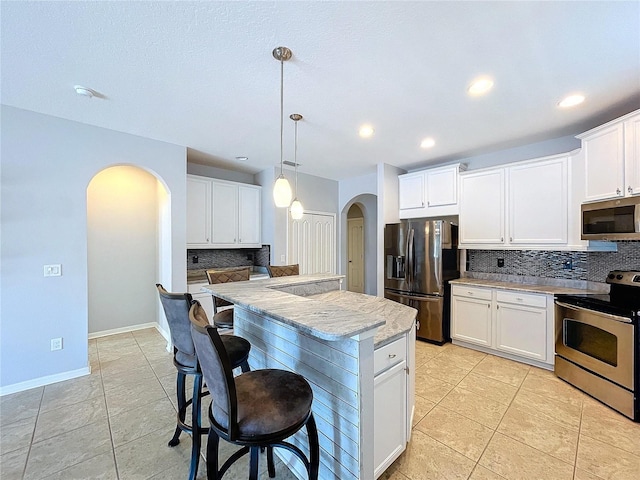 kitchen with a center island, decorative light fixtures, white cabinetry, stainless steel appliances, and light tile patterned flooring