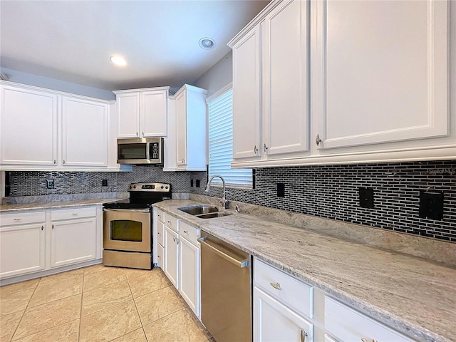 kitchen featuring light tile patterned floors, white cabinetry, appliances with stainless steel finishes, tasteful backsplash, and sink